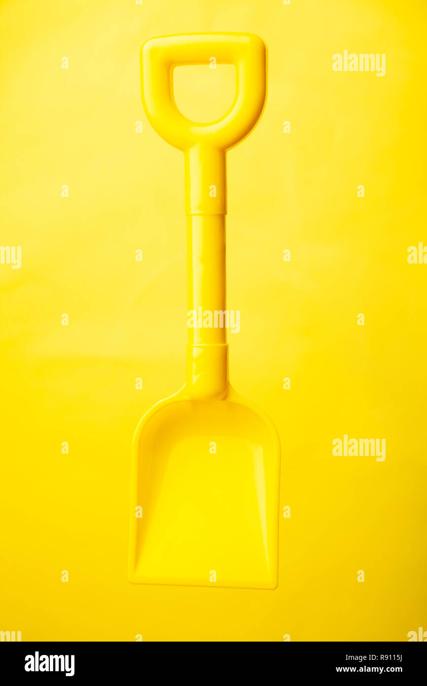 Ein Kunststoff gelb Spielzeug Spaten auf gelbem Hintergrund Stockfoto