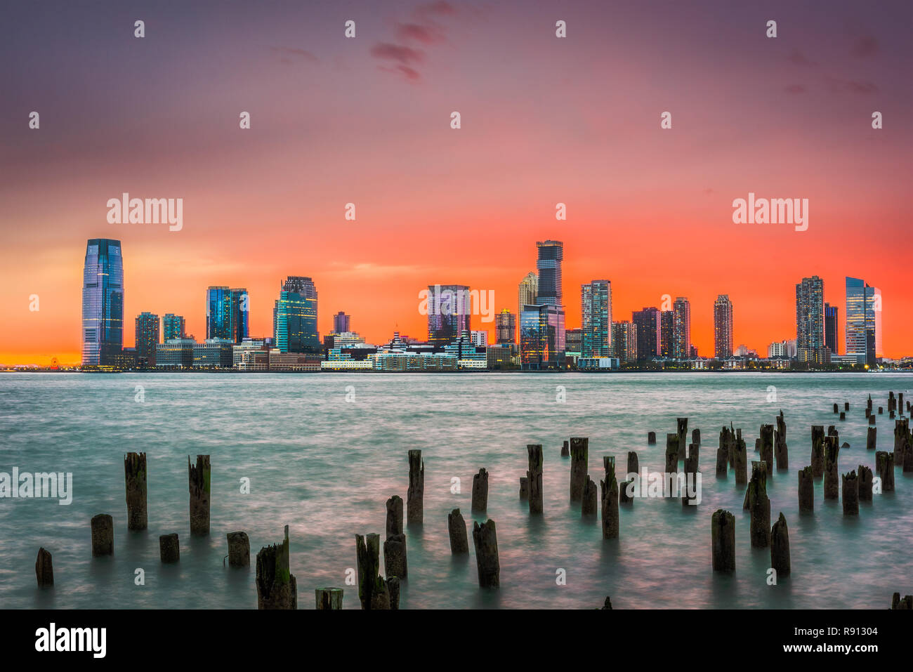 Jersey City, New Jersey, USA Skyline über den Hudson River nach Sonnenuntergang. Stockfoto