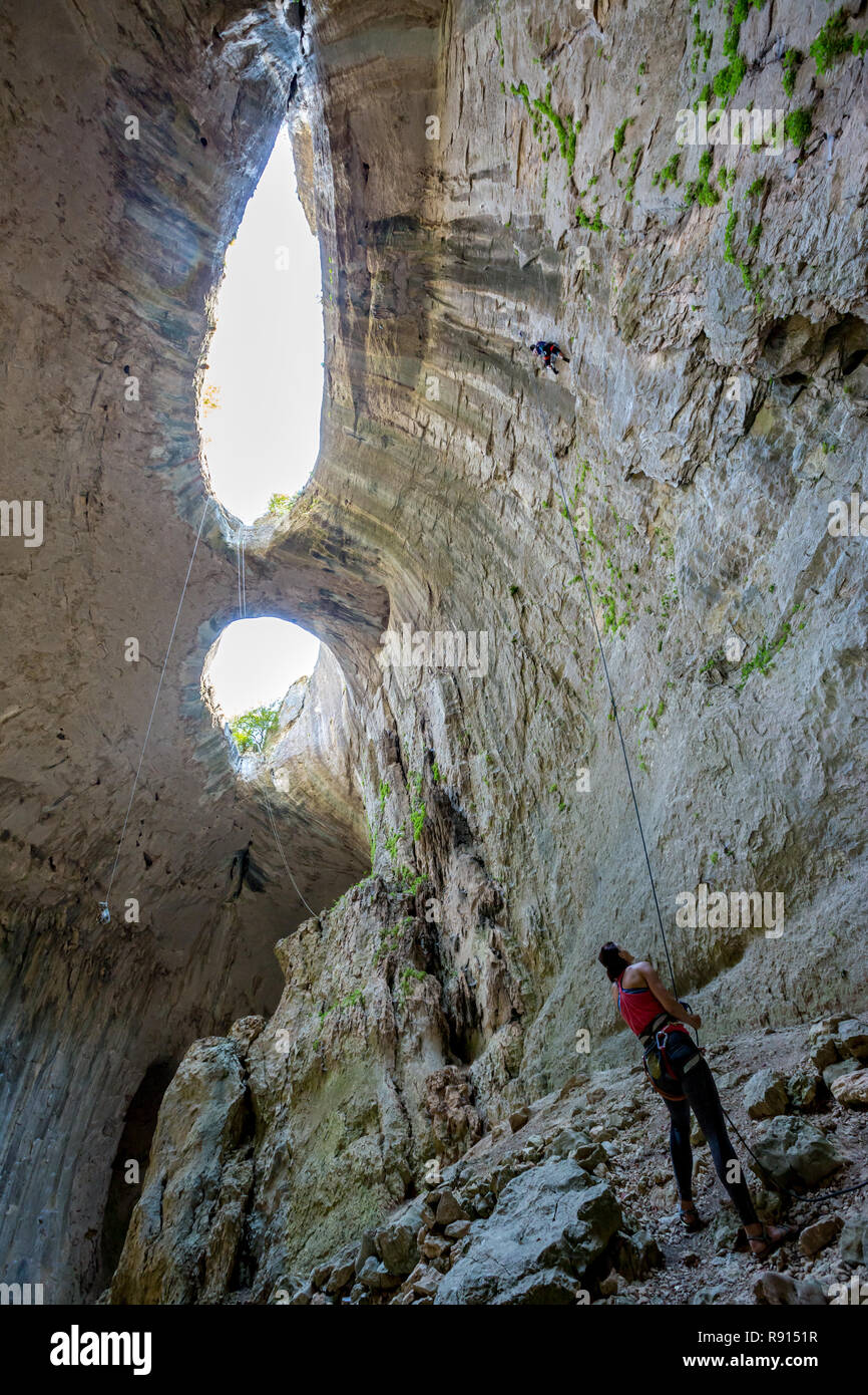 Paar unkenntlich furchtlose weibliche Höhle Kletterer in der prohodna Höhle, alias "die Augen Gottes", Norden von Bulgarien. Teamarbeit ist in diesem wichtigen Stockfoto