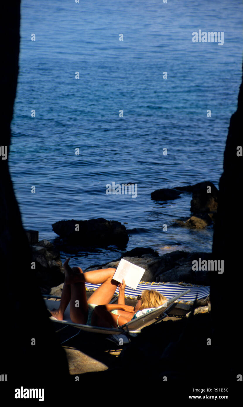 Frau auf einem Liegestuhl in Badehose ein Buch lesen, Sali, Dugi Otok, Kroatien Stockfoto