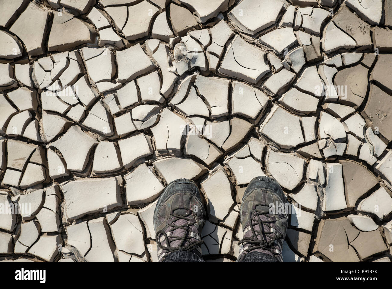 Füße treten auf trockenem Lehm aus einem Flussbett. Darstellung der trockenen globale Erwärmung Szenario Stockfoto