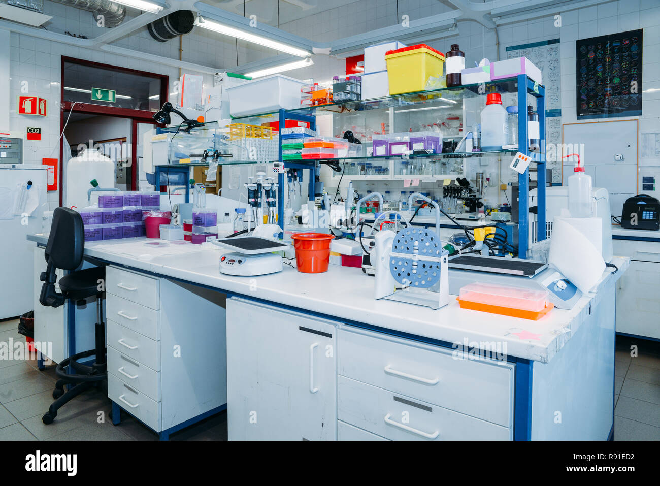 Innenraum der modernen Labor: Schreibtisch mit Petrischalen, Röhrchen, Fläschchen und moderne Mikroskop im Vordergrund Stockfoto