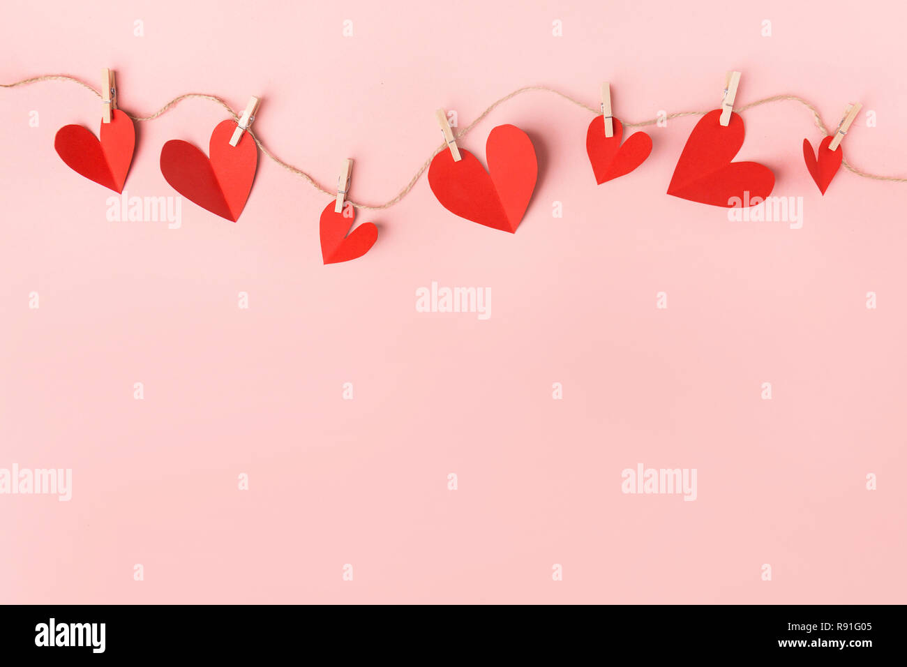 Schönen Valentines Tag Papier Herzen hängen am Seil auf rosa Hintergrund. Blick von oben. Valentines Tag Konzept. Stockfoto