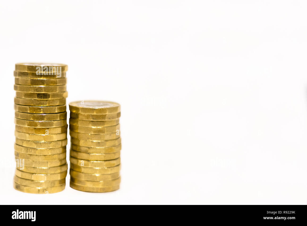 Stapel und Haufen von Britischen GBP goldenen Münzen Währung Geld auf weißem Hintergrund mit leeren Raum Stockfoto