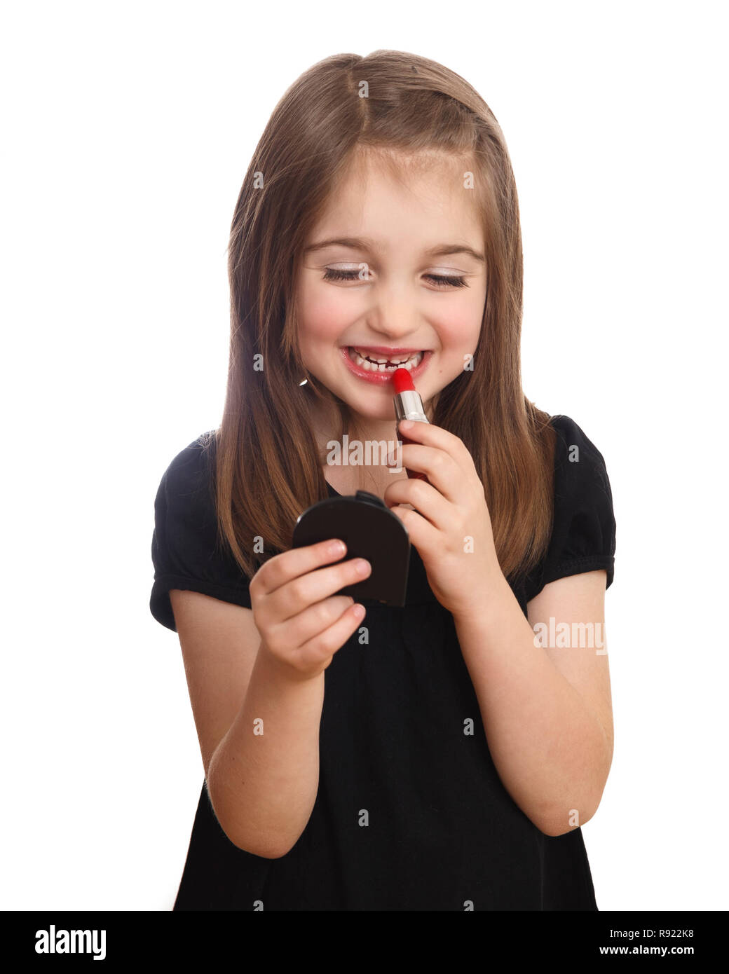 Nette junge Mädchen auf der Suche nach kompakten Spiegel setzen auf roten Lippenstift Stockfoto