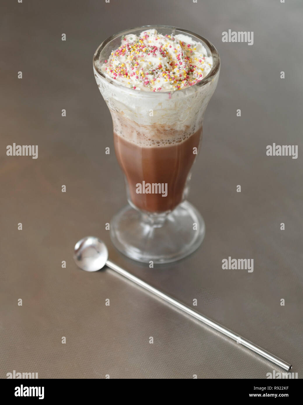 Großes Glas Heiße Schokolade mit Sahne und Streusel auf Edelstahl Hintergrund Stockfoto