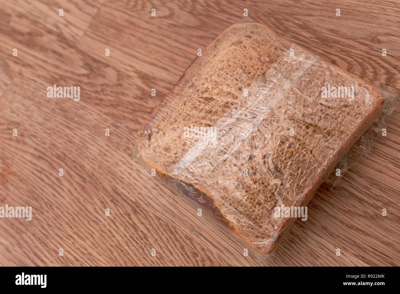 Bereit, Lunchpaket, bestehend aus Sandwich in Frischhaltefolie auf hölzernen Tisch Hintergrund gewickelt Stockfoto