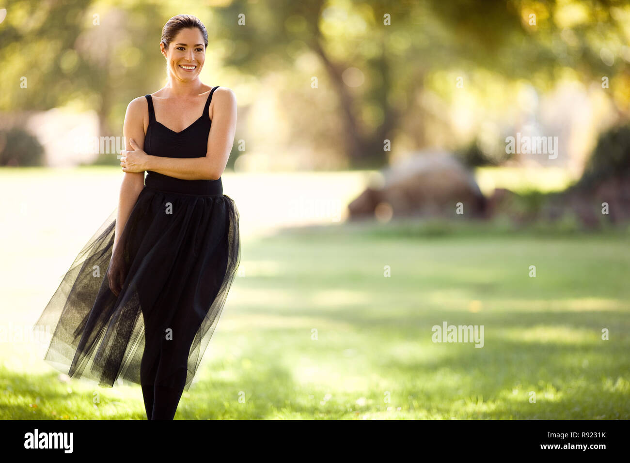 Mitte der erwachsenen Frau lächelnd, während in einem Park stehen. Stockfoto
