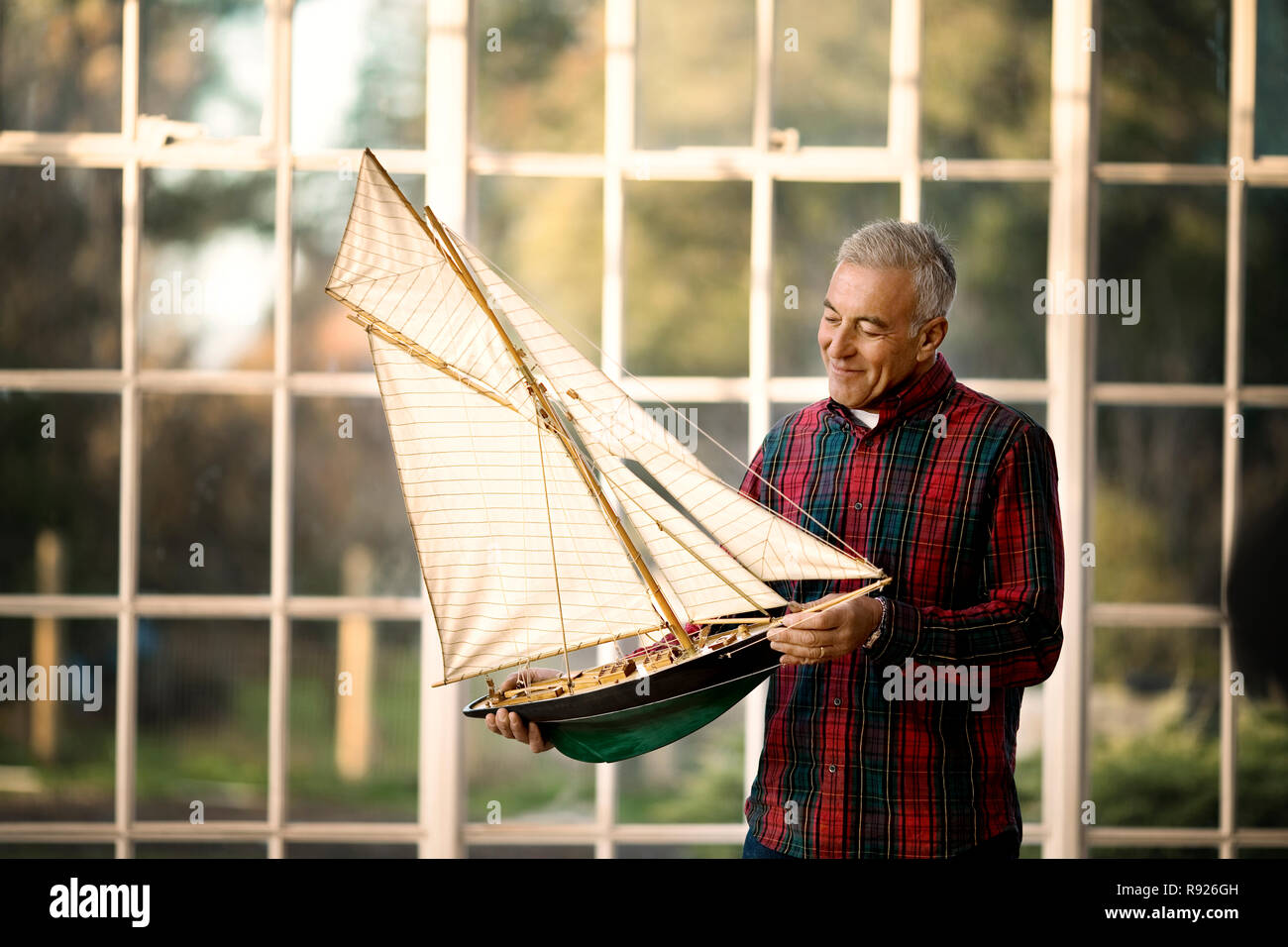 Nachdenklich auf der Suche älteren Mann hält ein Modell Boot. Stockfoto