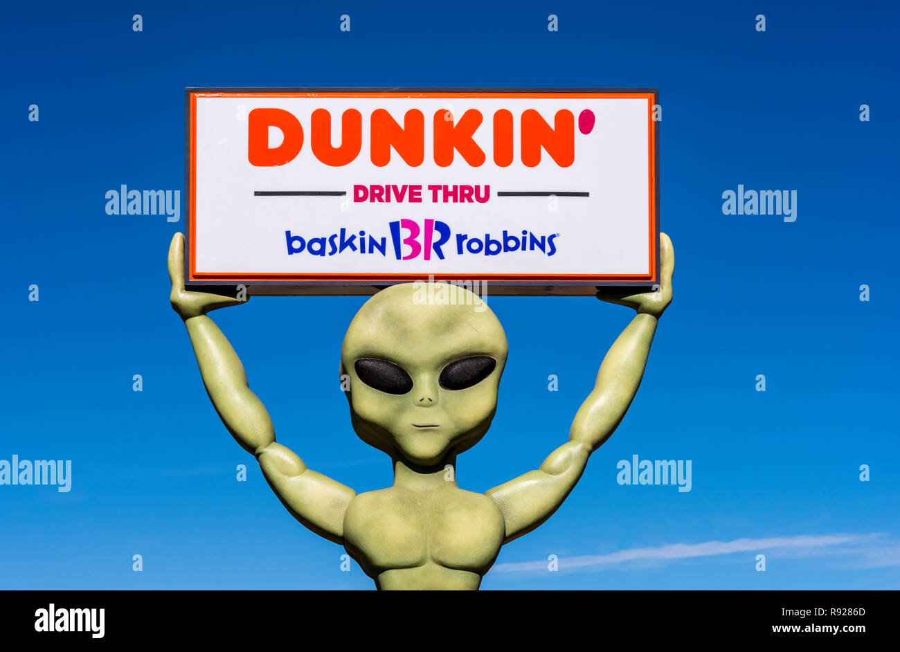 Roswell, New Mexico, USA, riesige grüne Alien hält einen Dunkin' Donuts und Baskin Robbins unterzeichnen. Stockfoto