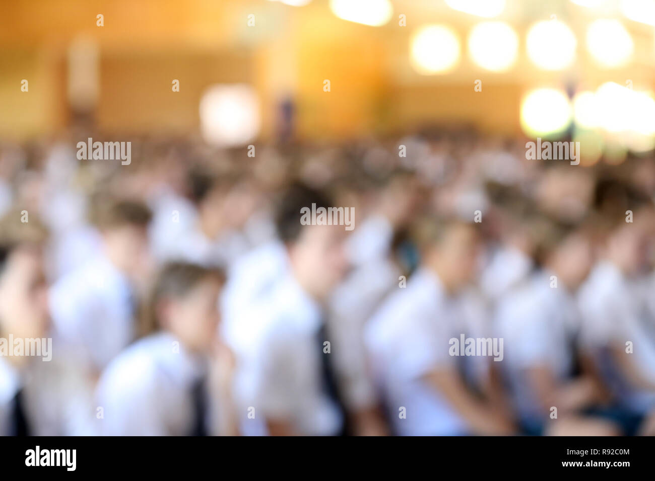 Absichtlich unscharf verschwommenes Bild der Großen Halle voller High School Studenten in weißem Hemd und Krawatte Uniformen hören bei der Montage. Stockfoto