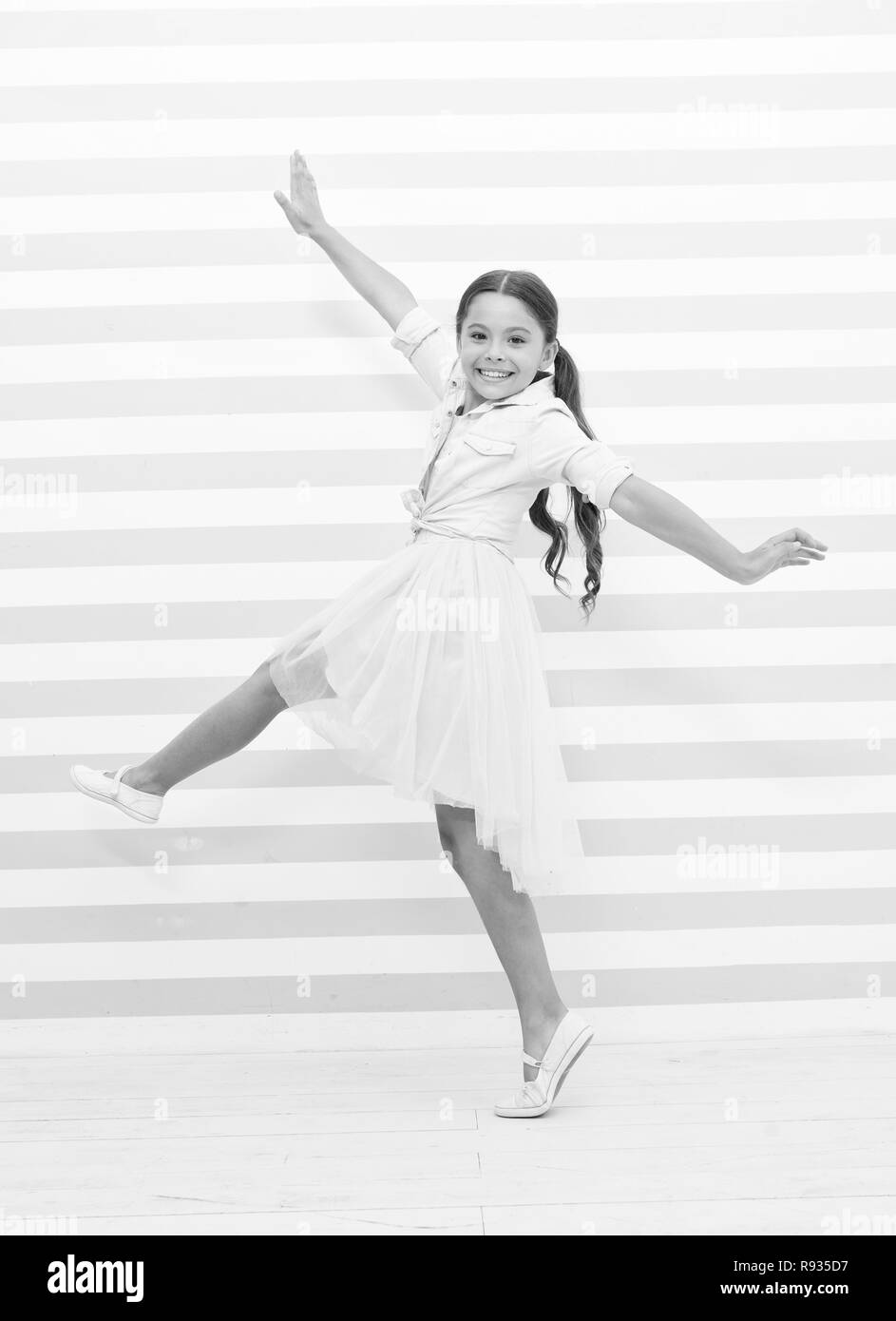 Kind Konzept. Glückliches Kind tanzen. Kind, Mädchen, Lächeln in Mode Kleid. Kind und Kindheit. Gefühl der Freiheit. Stockfoto