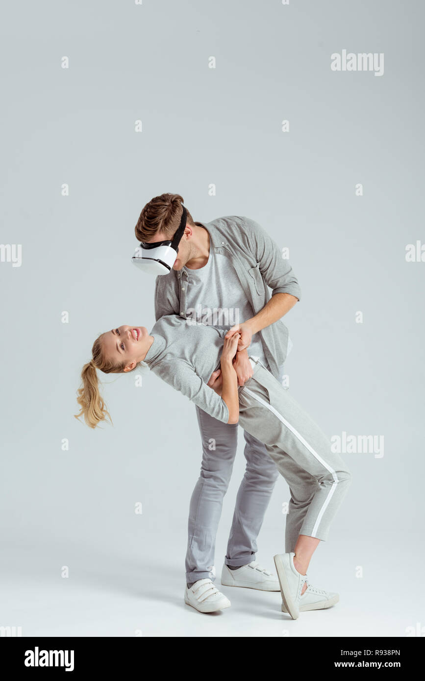 Mann, Frau, umarmen, während in der virtuellen Realität auf grauem Hintergrund Stockfoto