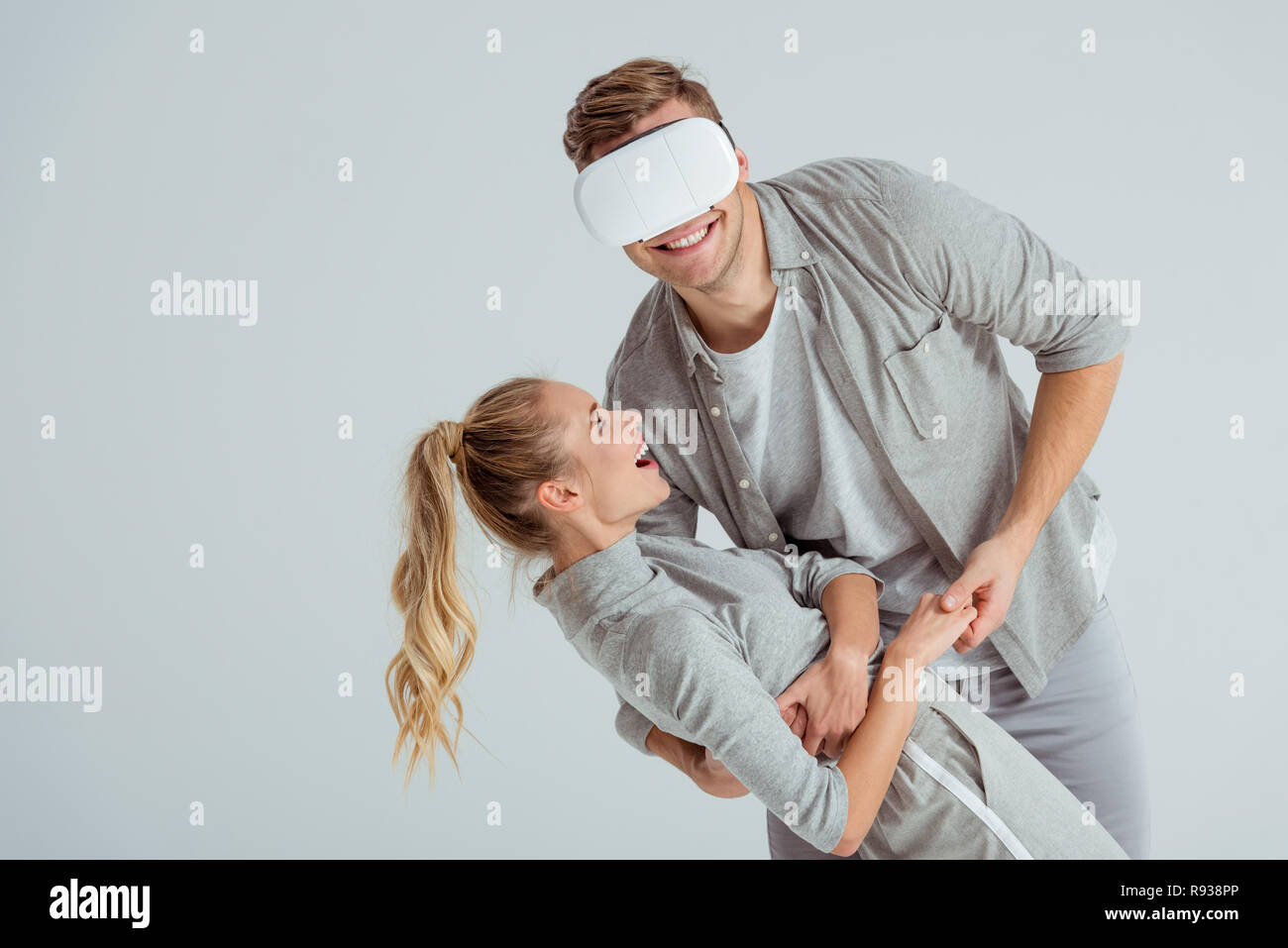Mann, Lächeln, Frau, umarmen, während in der virtuellen Realität isoliert auf Grau Stockfoto