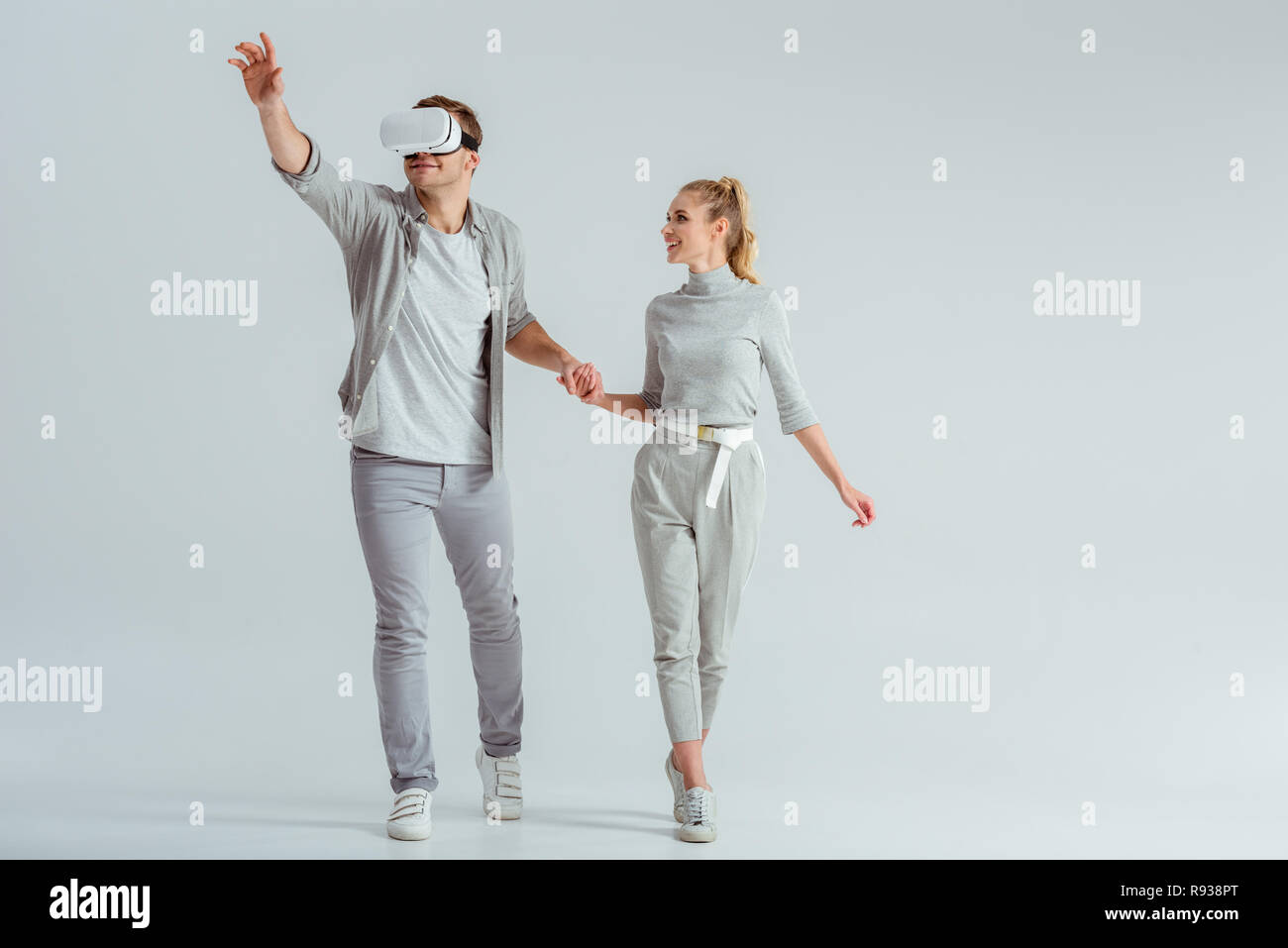 Paar Hände halten während man erleben virtuelle Realität und gestikulierend auf grauem Hintergrund Stockfoto