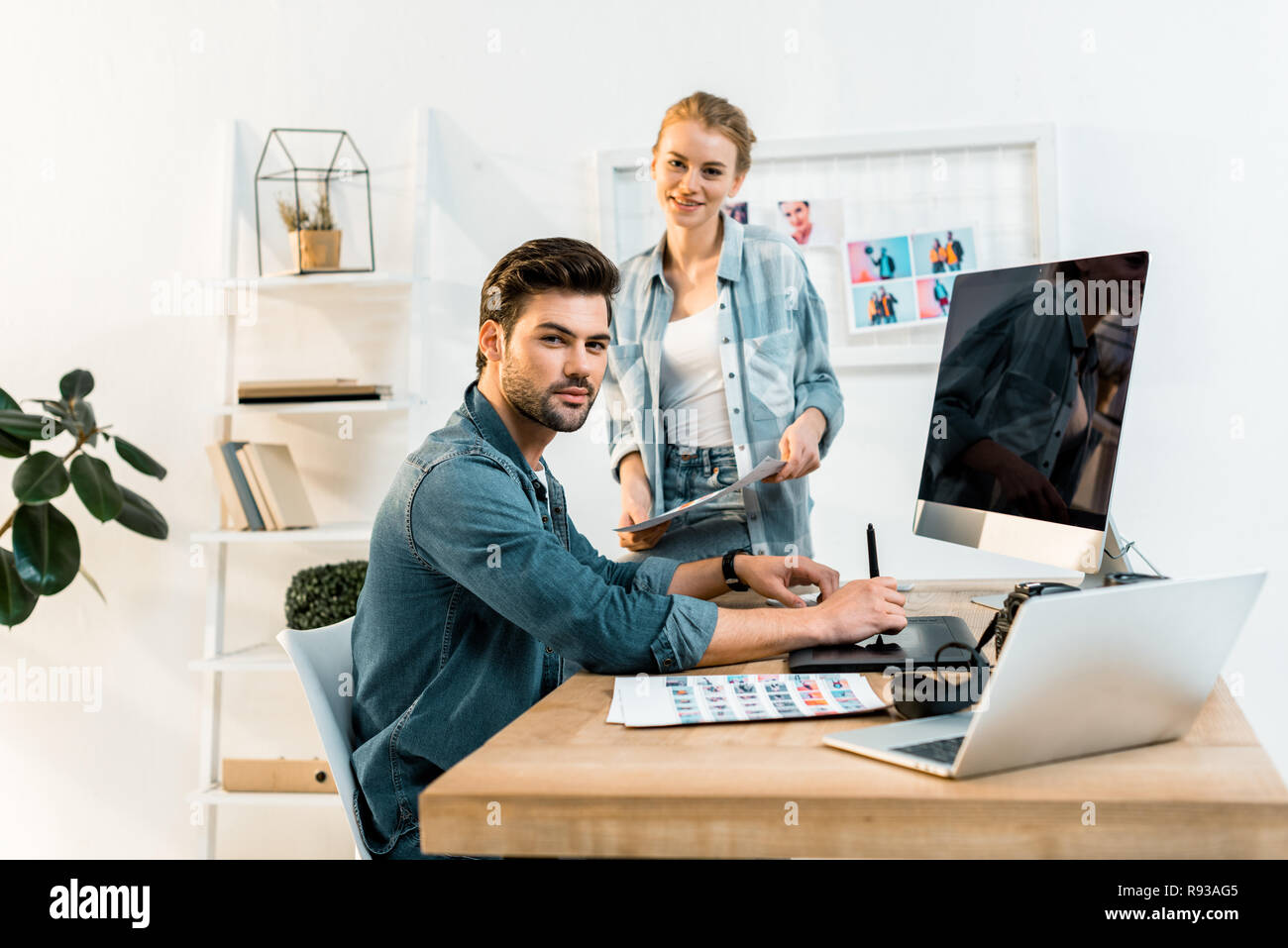 Junge Fotografen lächeln auf die Kamera beim Retuschieren von Fotos im Büro Stockfoto