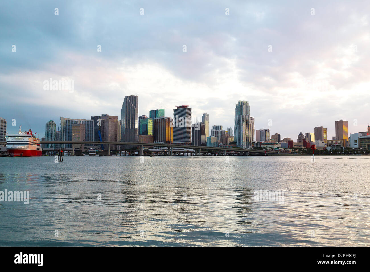 Miami Skyline der Stadt mit Brücke und Kreuzfahrtschiff bei Sonnenuntergang mit bewölktem Himmel. Urban Panorama von Miami City am Abend. Stockfoto