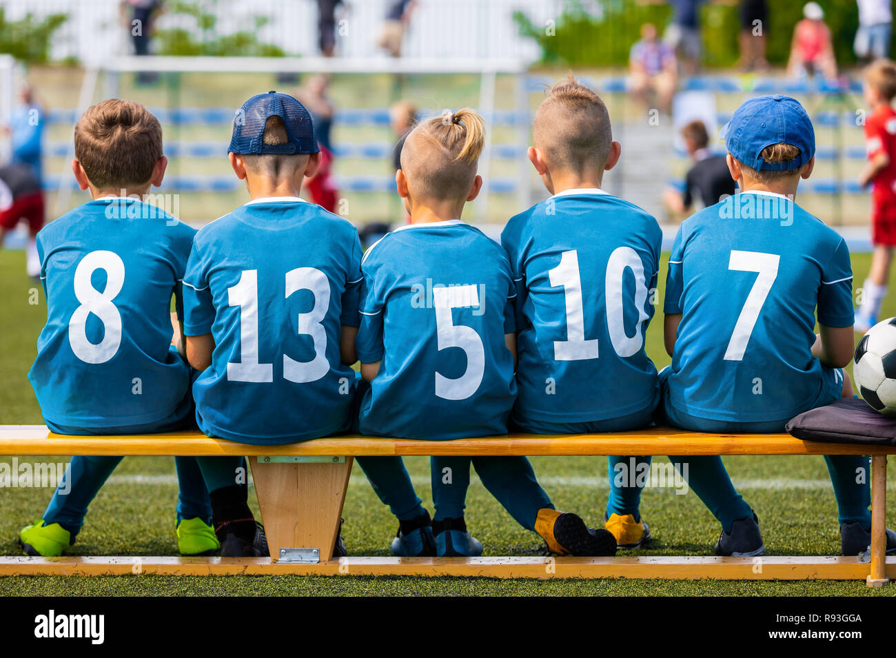 Kinder- Fußball-Mannschaft während des Spiels. Jungen Fußball-Team Mitglieder sitzen auf Fußball-Bank, auf der Rasenfläche. Kinder Fußball Mannschaft mit Ball auf dem Stockfoto