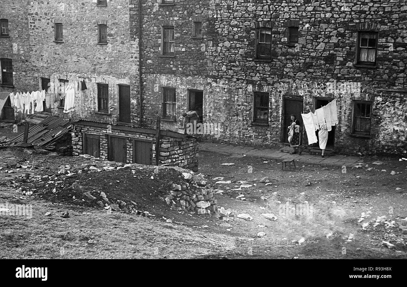 Mitte der 1940er Jahre, slum Gehäuse in Merthyr, South Wales, UK. Der Niedergang der lokalen Stahl und Kohle in den 1930er Jahren und dann wieder nach WW2 bedeutete Migration und Arbeitslosigkeit und große Armut und Not gelitten, mit schlechte Wohnverhältnisse und Lebensbedingungen. Hier sehen wir die lokalen Frauen setzen ihre Wäsche auf einer Wäscheleine außerhalb ihrer Häuser. Stockfoto