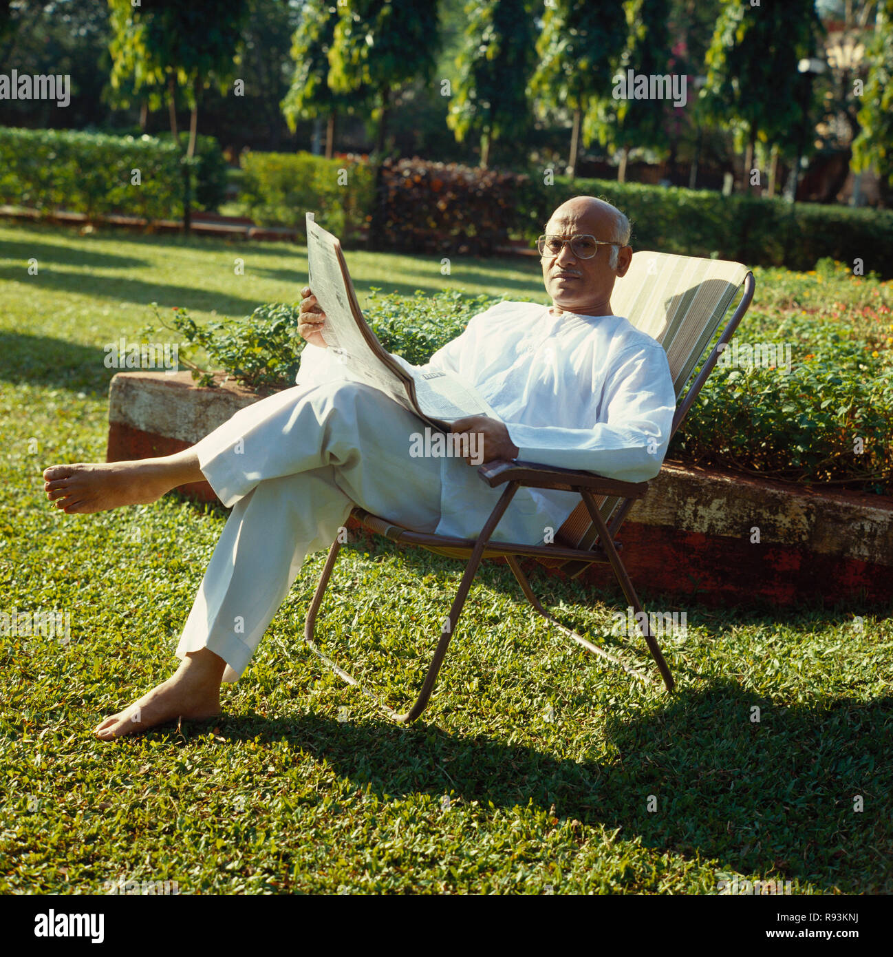 Senioren Zeitung lesen, alter Mann im Garten sitzen, Indien, Asien Stockfoto