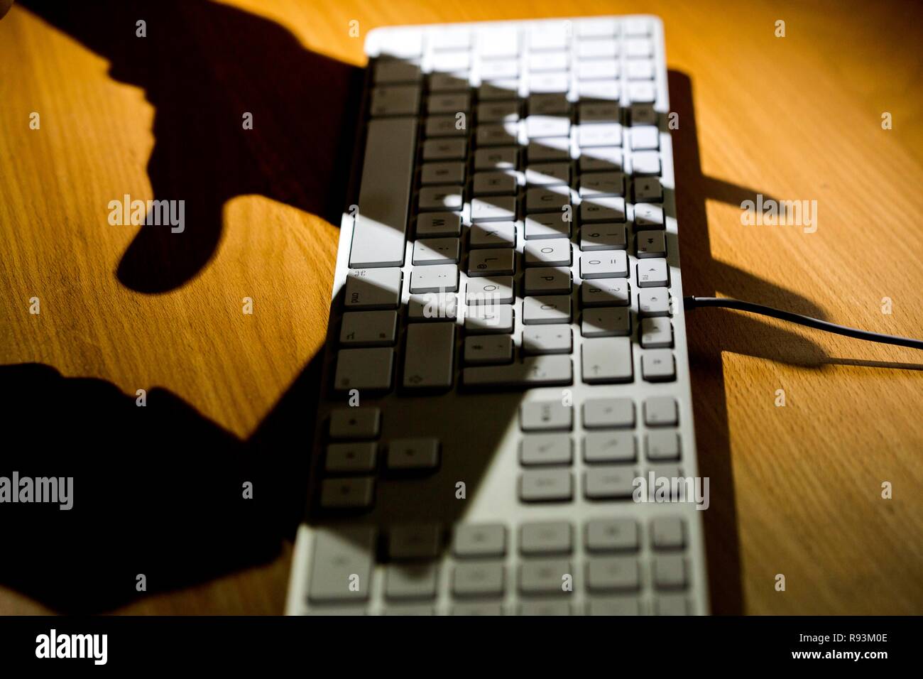 Schatten der zwei Hände auf die Tastatur eines Computers, einer Hand, die eine Kreditkarte, symbolische Bild für Cyberkriminalität, Datensicherheit Stockfoto