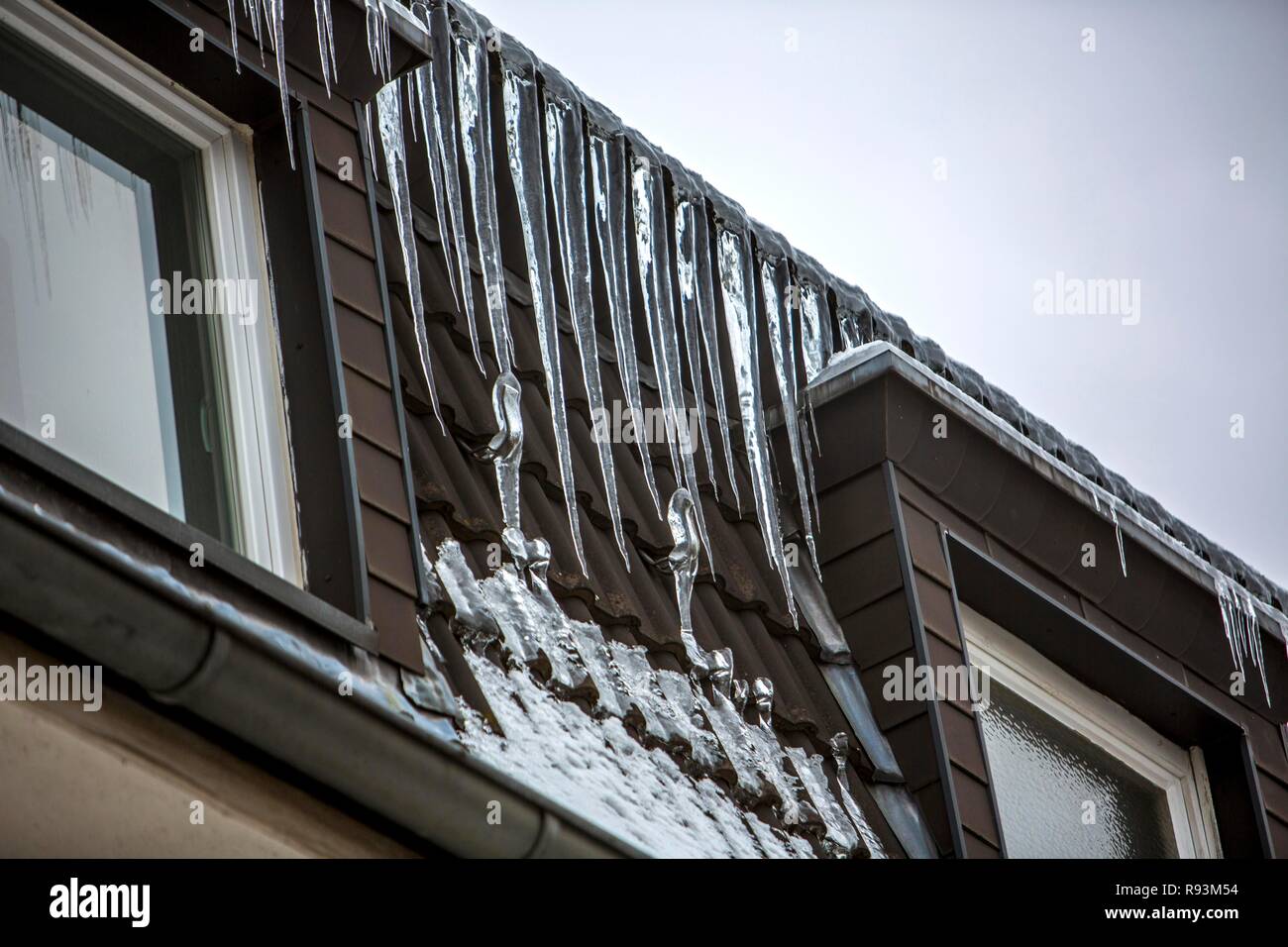 Große Eiszapfen hängen von der Traufe eines Hauses, Zeichen eines schlecht wärmegedämmten Dach, Essen, Nordrhein-Westfalen, Deutschland Stockfoto