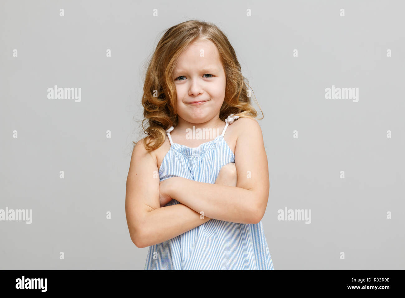 Porträt eines kleinen Mädchens auf einem grauen Hintergrund. Kind ist wütend Stockfoto