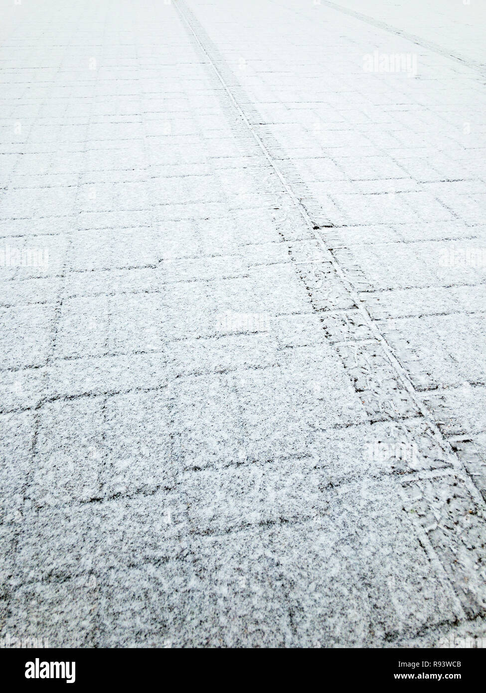 Fliesen- Pflaster bedeckt mit ersten Schnee. reifenspur Impressum auf der Oberfläche der Bürgersteig Stockfoto