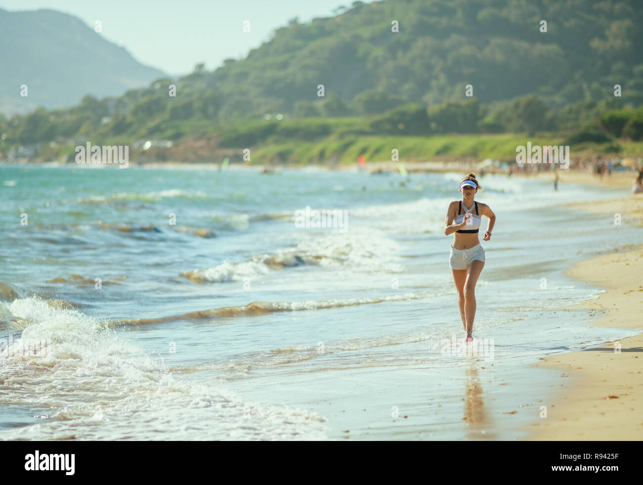 Aktive Frau Jogger in Fitness Kleidung auf das Meer am Abend läuft. Strand joggen ist Herausforderung für den ganzen Körper. instabilen Oberfläche und aus Stockfoto