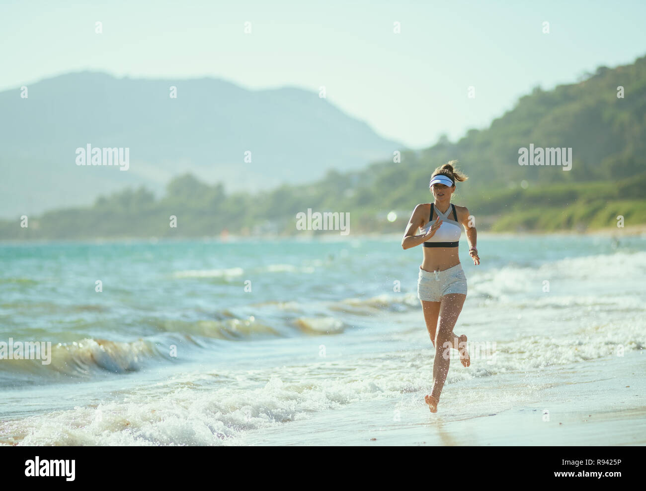 Gesund sport Frau in Fitness Kleidung auf das Meer am Abend joggen. vom Stress in der Stadt in Ocean Shore ein Höchstmaß an phys erreicht Stockfoto