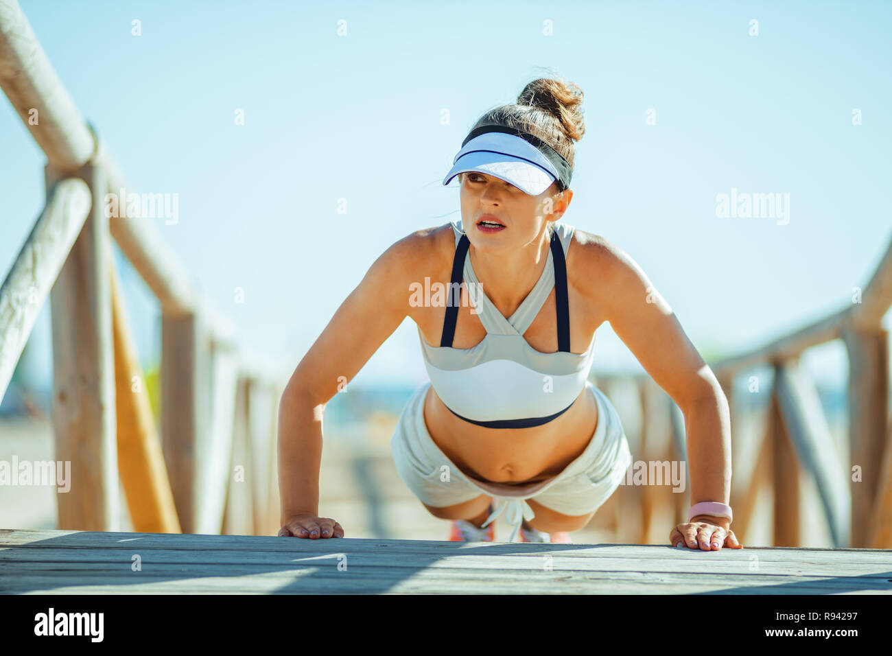 Passende Frau Jogger in Fitness Kleidung auf der Seeküste pushups zu tun. 30 Jahre alt fitness Frau der Stärke-Programm und Liegestütze Stockfoto