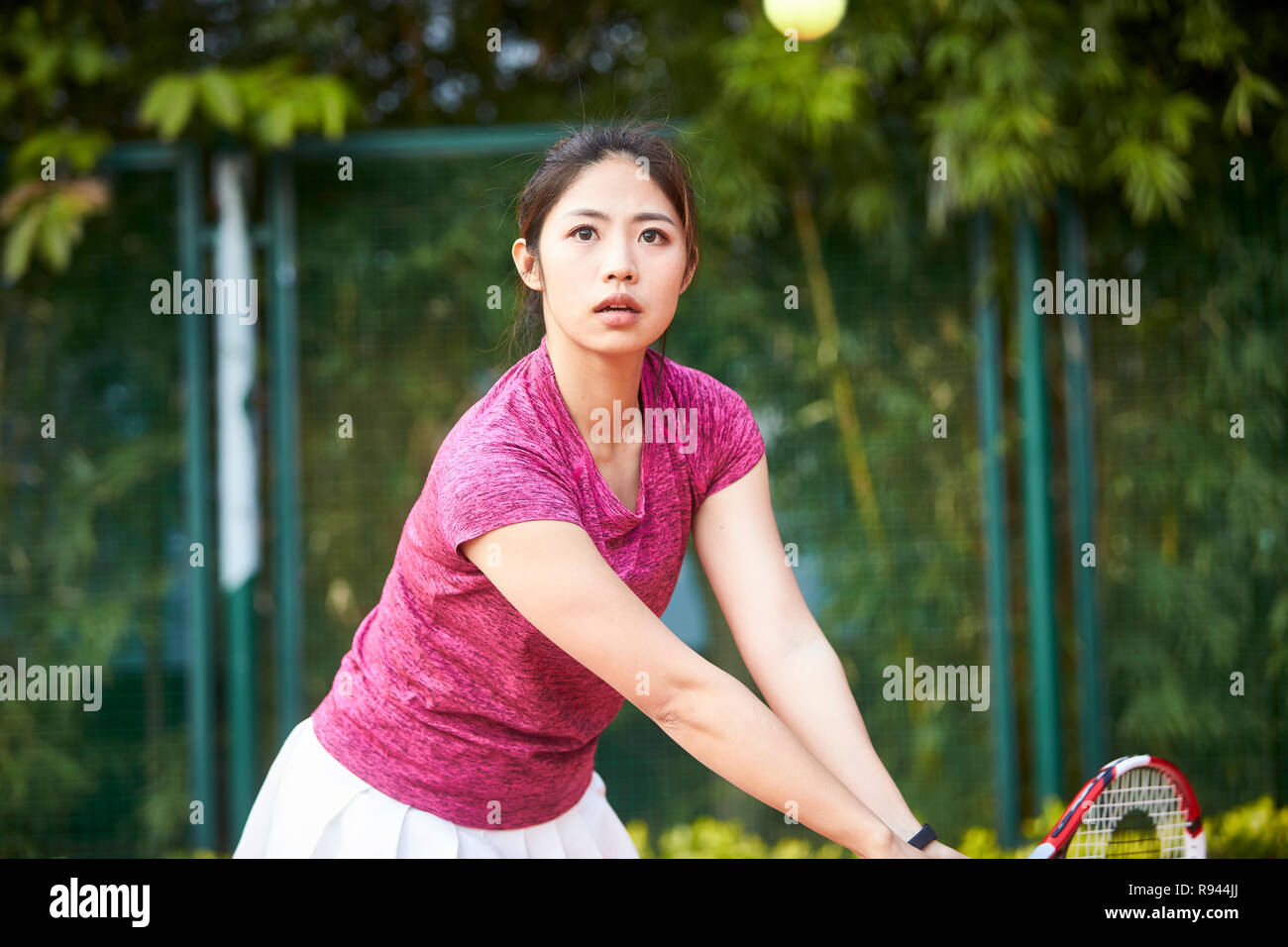 Junge asiatische Frau weibliche Tennisspieler schlagen den Ball mit der Rückhand Stockfoto