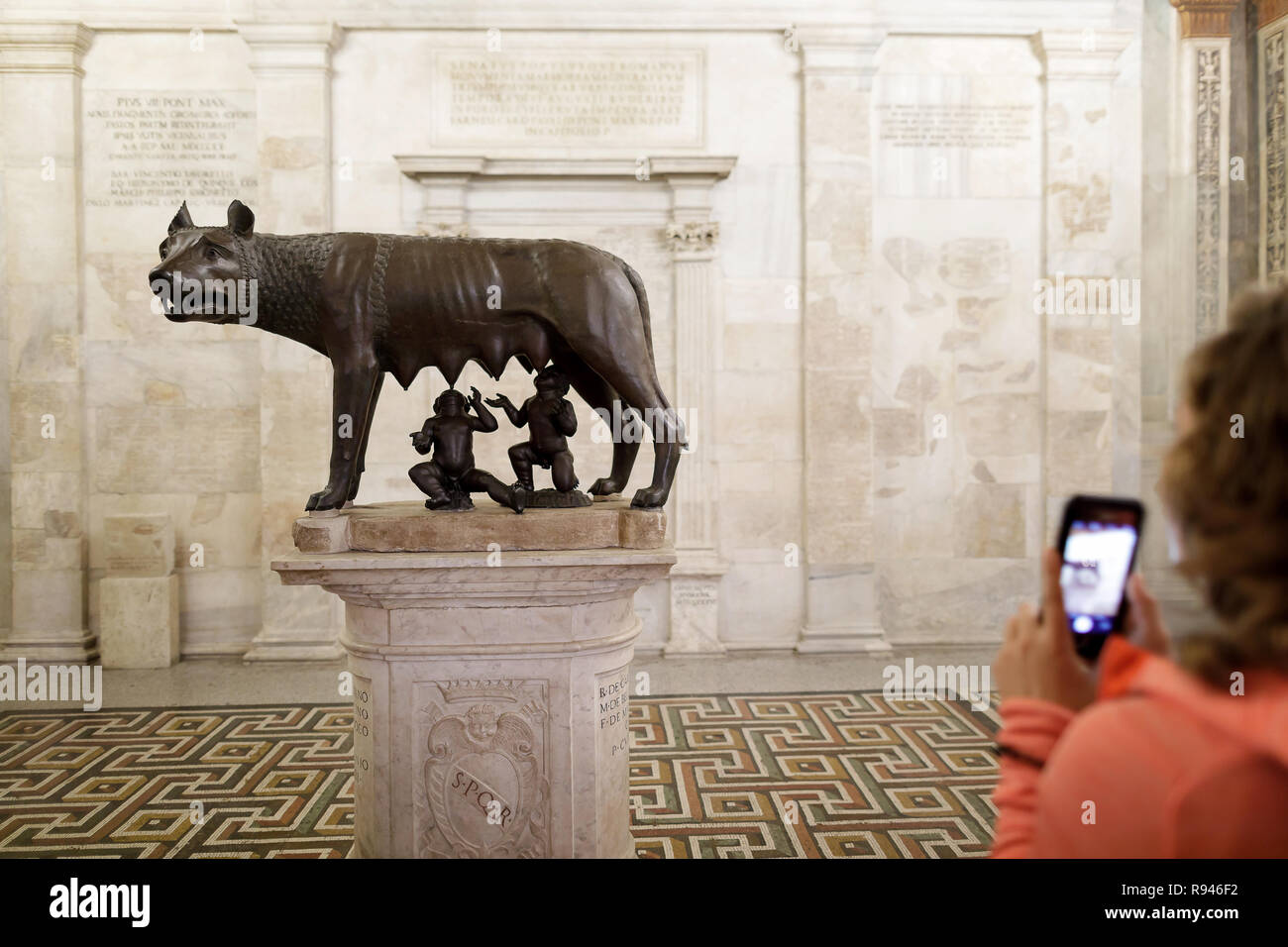 Die Statue der Wölfin, Symbol von Rom, in einem Raum des Kapitolinischen Museen, während von einem Touristen fotografiert werden. Stockfoto
