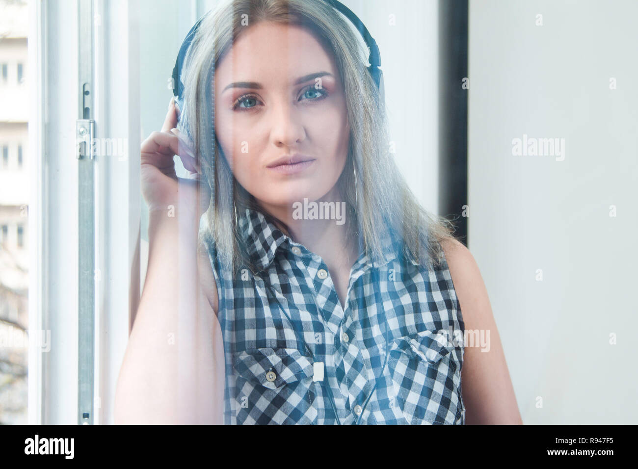 Schöne Mädchen in Plaid Shirt mit Kopfhörern Musik hören in Innenräumen, unscharfen Hintergrund, Kopf und Schultern, Jugend Musik Konzept Stockfoto