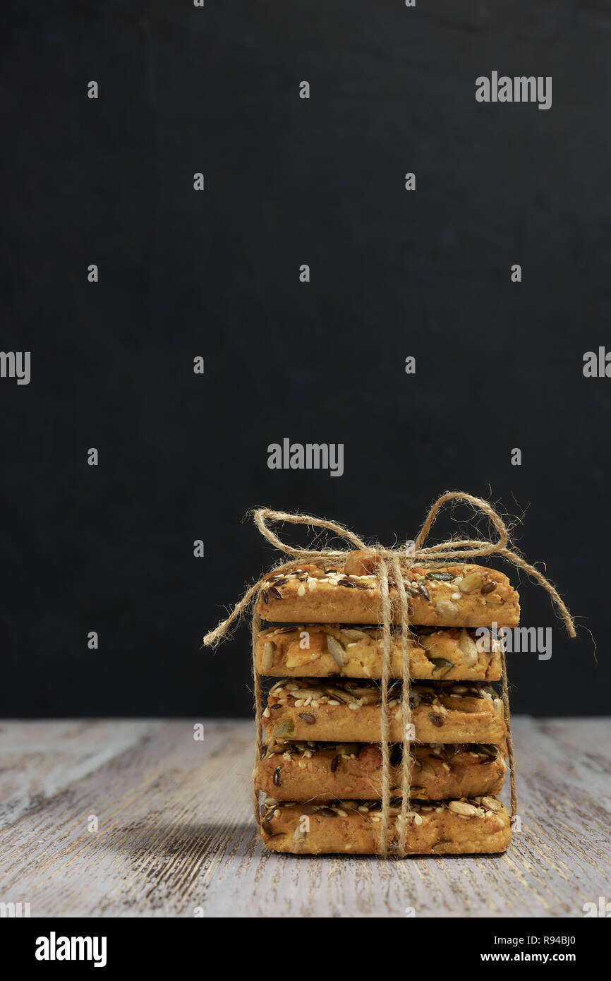 Ein von Shortbread Cookies mit verschiedenen Arten von Nüssen Stack mit einem köstlichen Kaffee oder Tee auf einem dunklen Holztisch. horizontale Ansicht. Stockfoto
