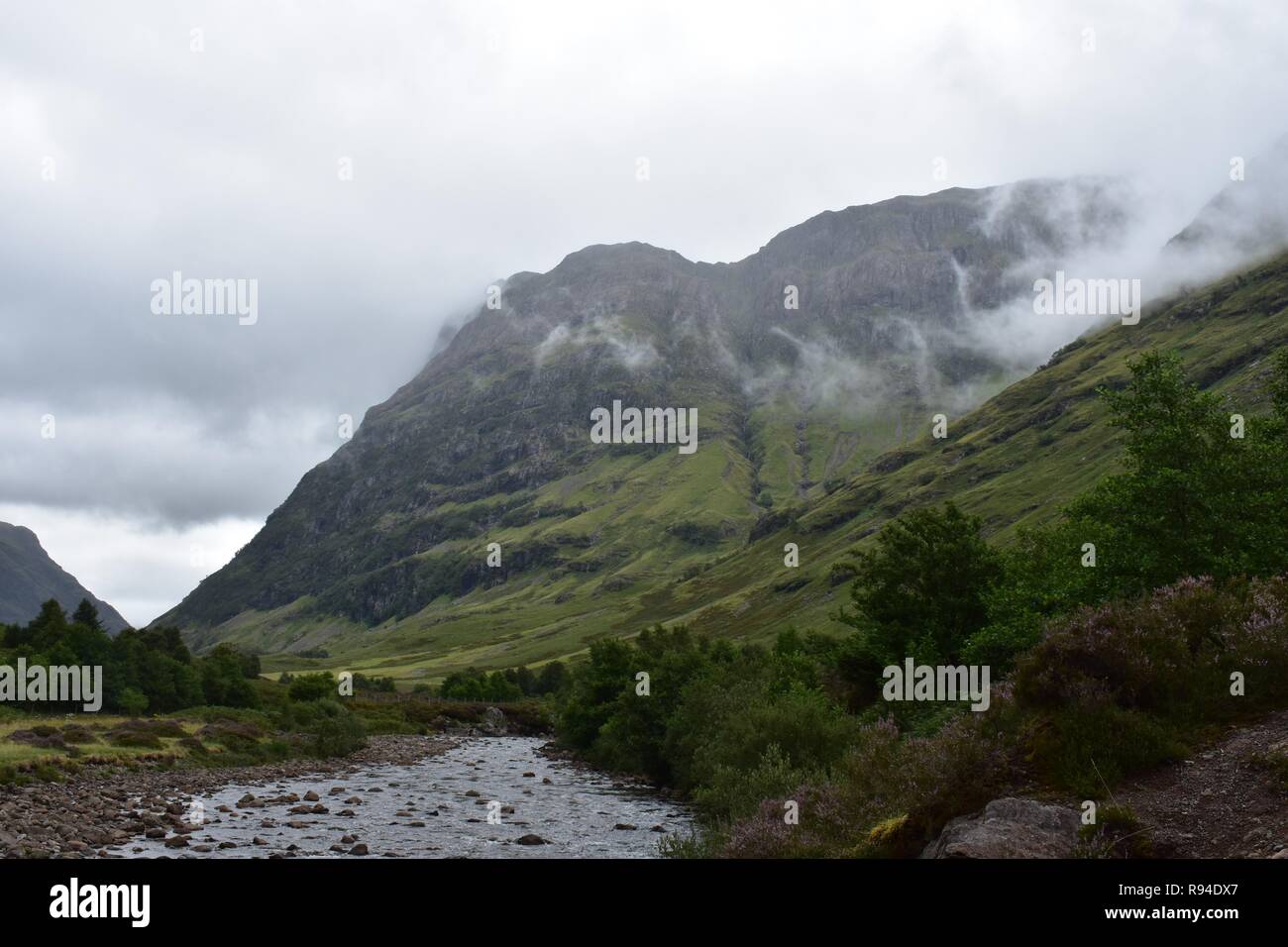 Coe fließt der Fluss durch das Tal von Glencoe Mountain Range in den schottischen Highlands. Auf einen Regen und bewölkt August Tag genommen. Stockfoto