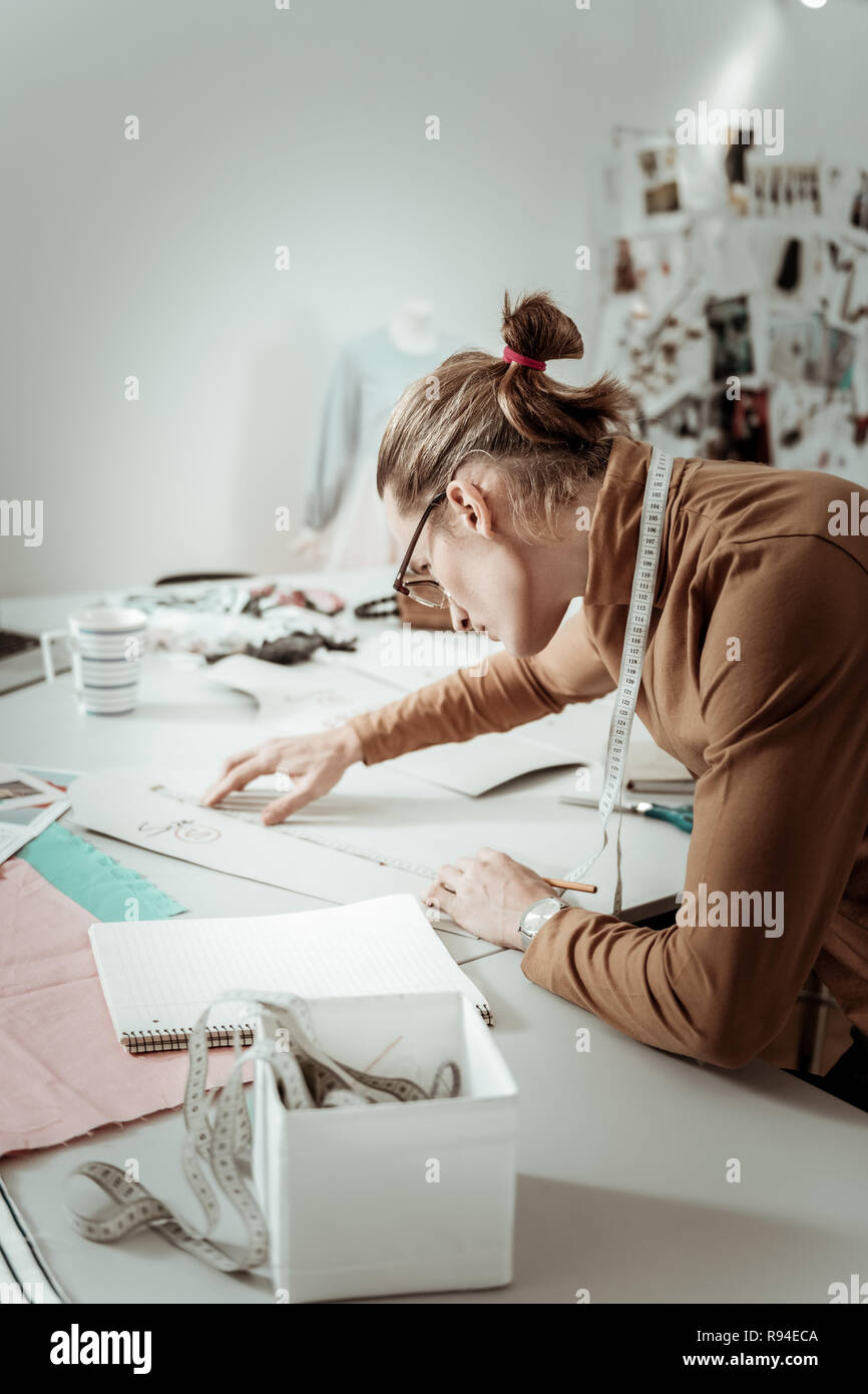 Hübscher junger Designer aus einer Modeschule in Brillen arbeiten mit Skizzen Stockfoto