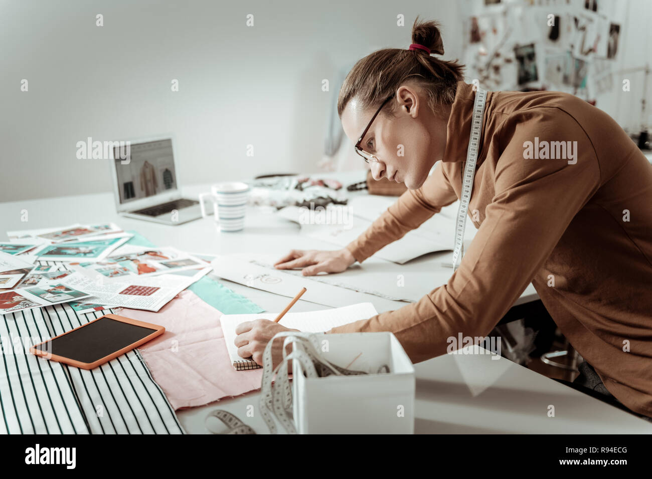 Hübscher junger Designer aus einer Modeschule in Brillen notieren Messungen Stockfoto