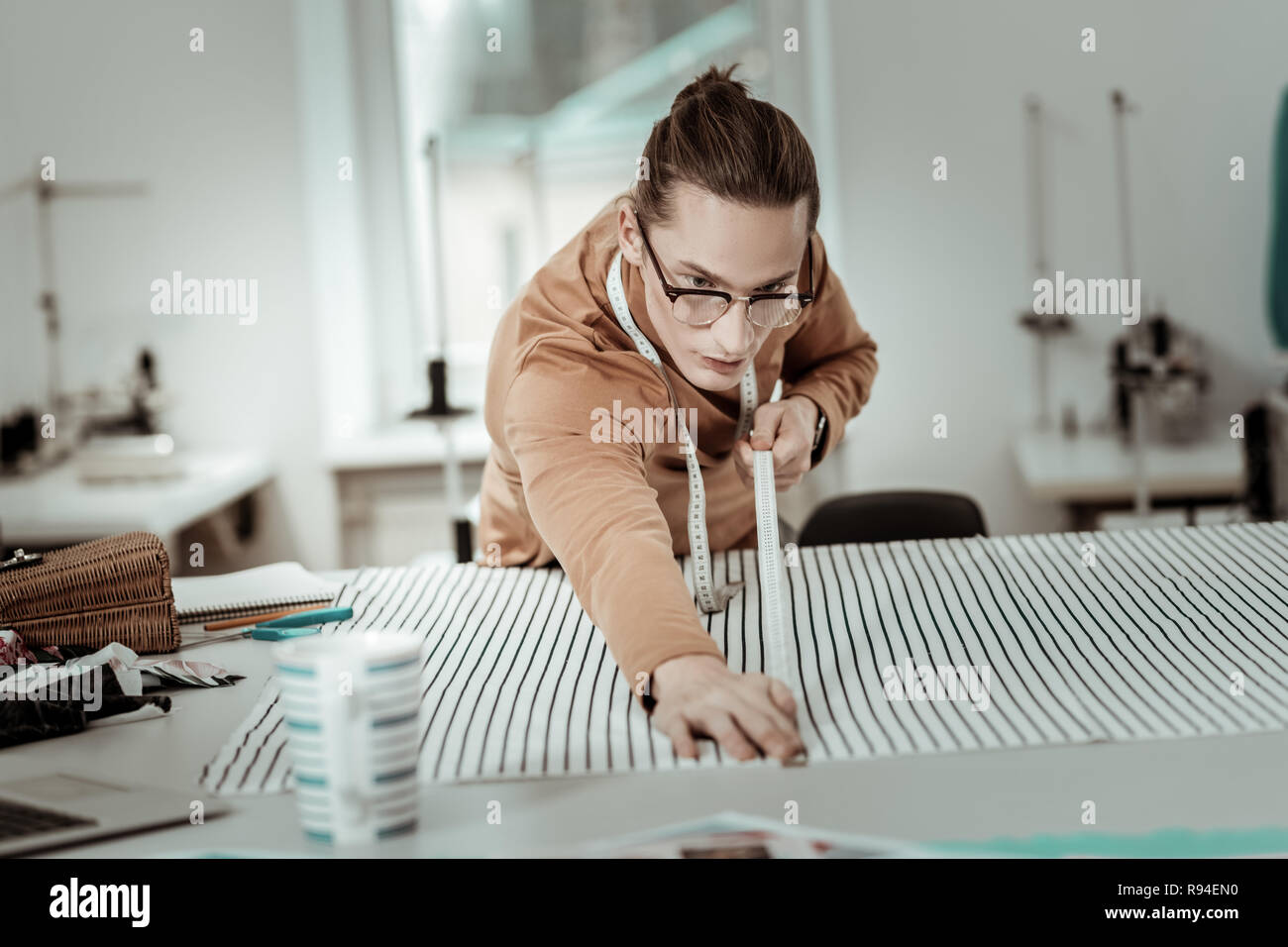Junge schöne Designer Brillen mit langen Haaren arbeiten mit Textilen Stockfoto