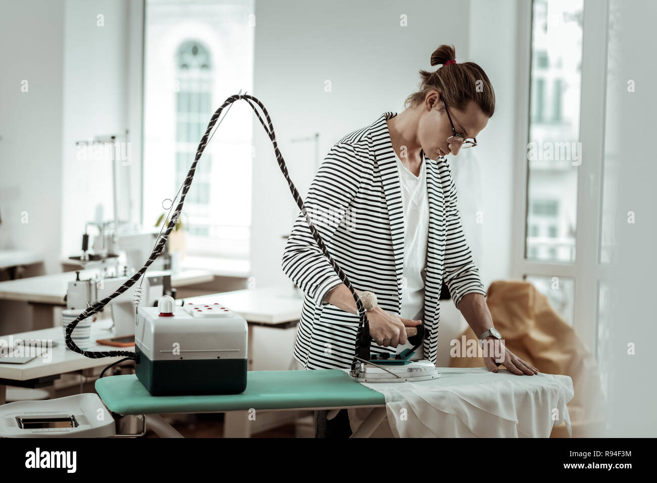 Young Fashion Designer von Generation Y mit langen Haaren auf der Suche konzentriert Stockfoto
