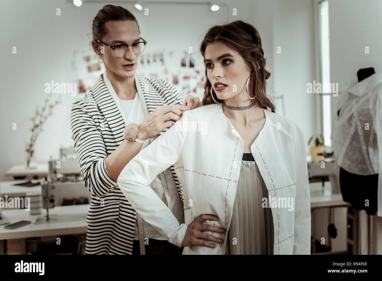 Hübsche dunkelhaarige Modell mit breiter Augenbrauen, die versuchen, auf einem weißen Jacke Stockfoto