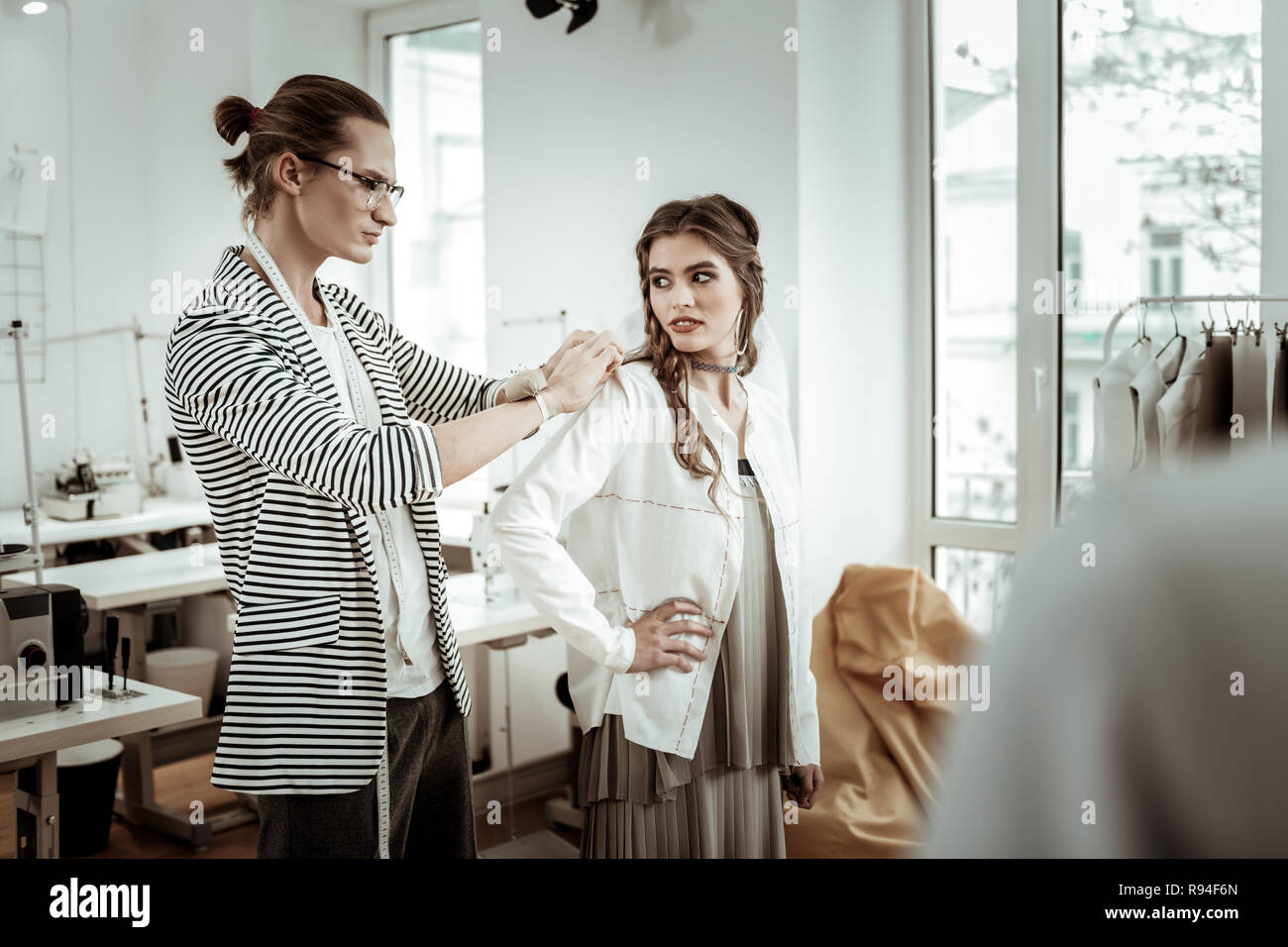 Hübsche dunkelhaarige Modell mit breiter Augenbrauen, die versuchen, über eine neue Jacke Stockfoto