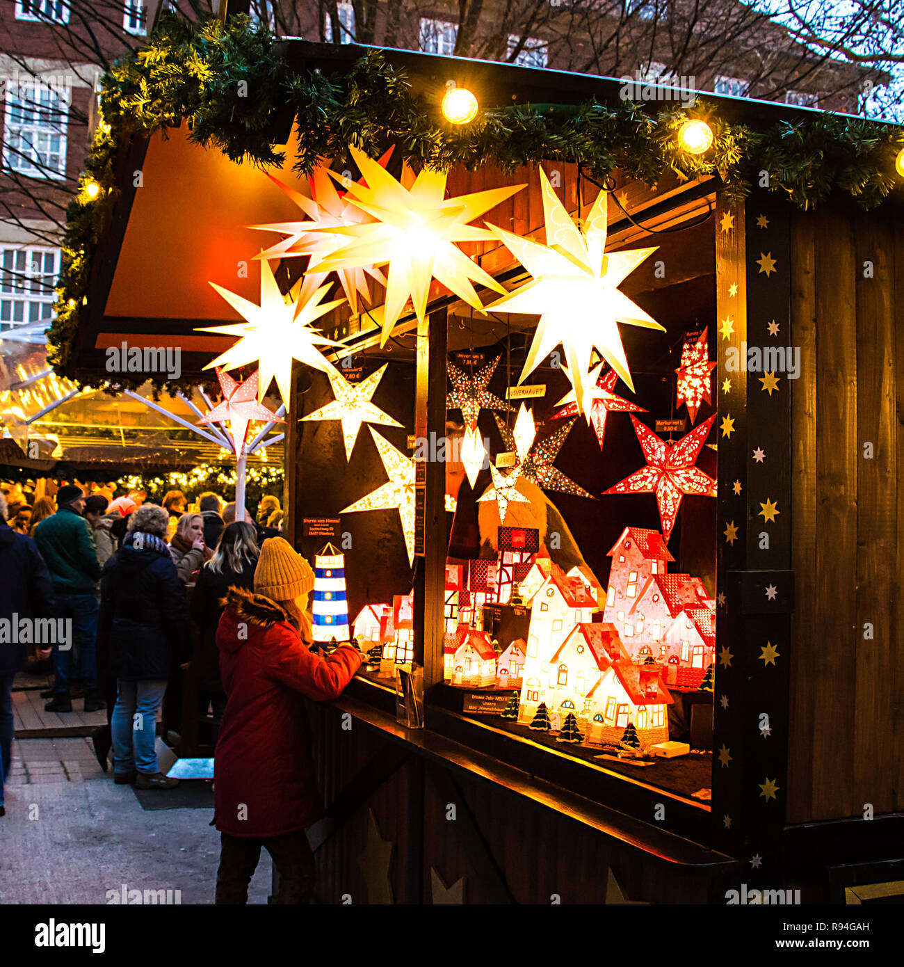 Ein Mädchen sieht in einem Stall Verkauf von hübschen sternförmigen Leuchten, Lampenschirme und Dekorationen auf dem Weihnachtsmarkt in Münster, Deutschland Stockfoto