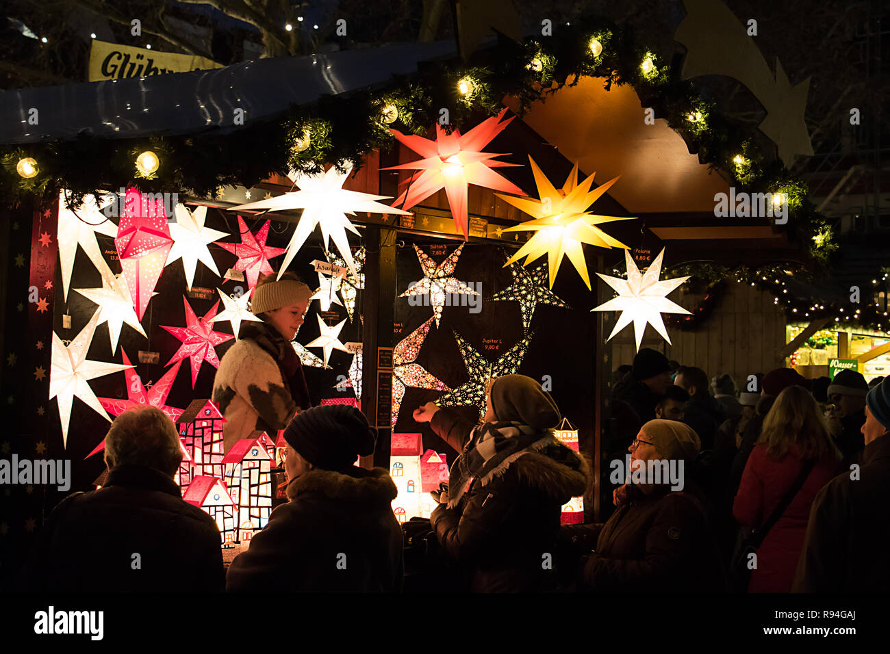 Menschen bewundern einen Stall Verkauf von hübschen sternförmigen Lampenschirme, Lampen und Dekorationen auf dem Weihnachtsmarkt in Münster, Deutschland Stockfoto