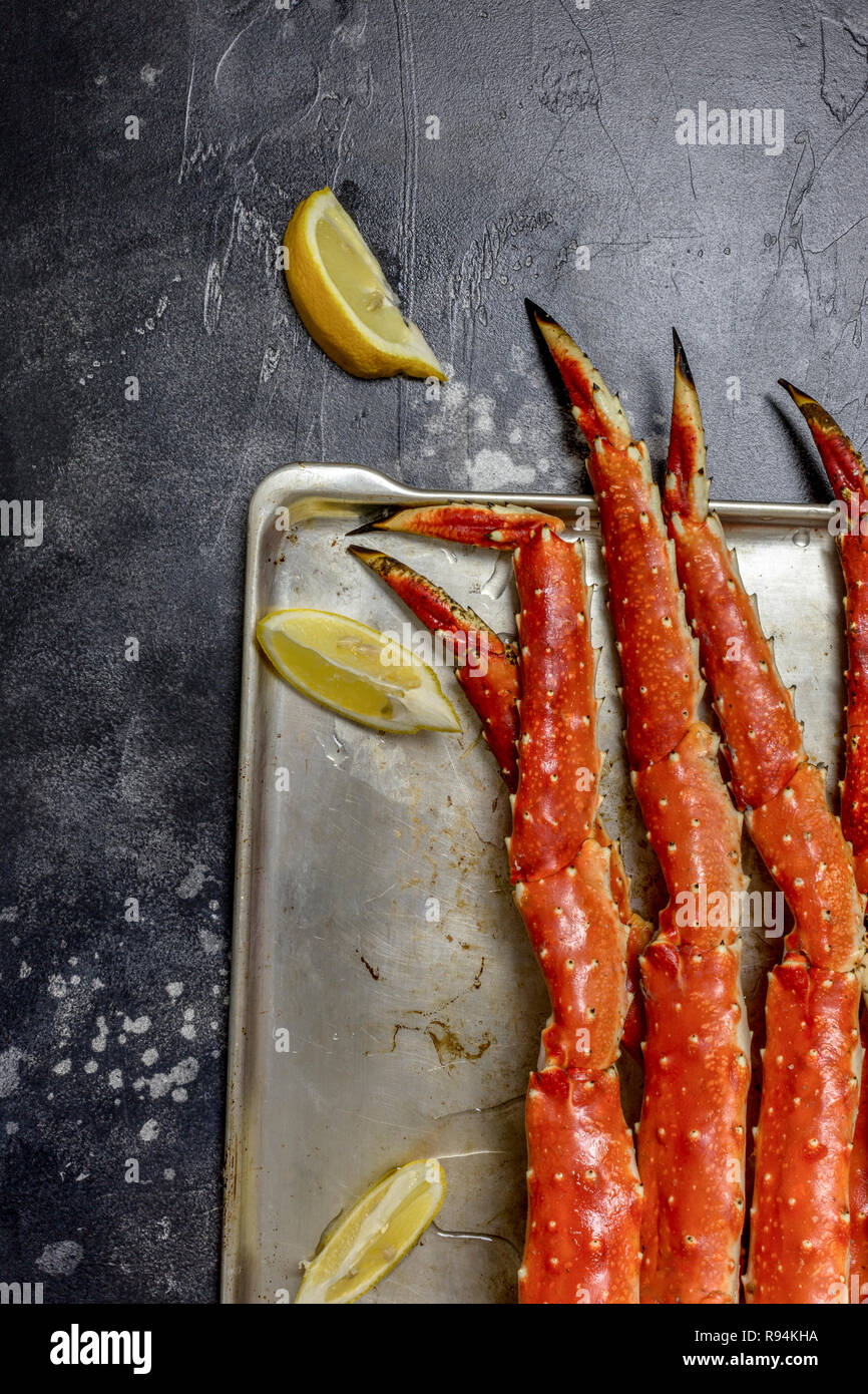 Luxury King snow Crab Claw mit Zitrone am Metallauflagefach auf schwarzem Hintergrund Stockfoto