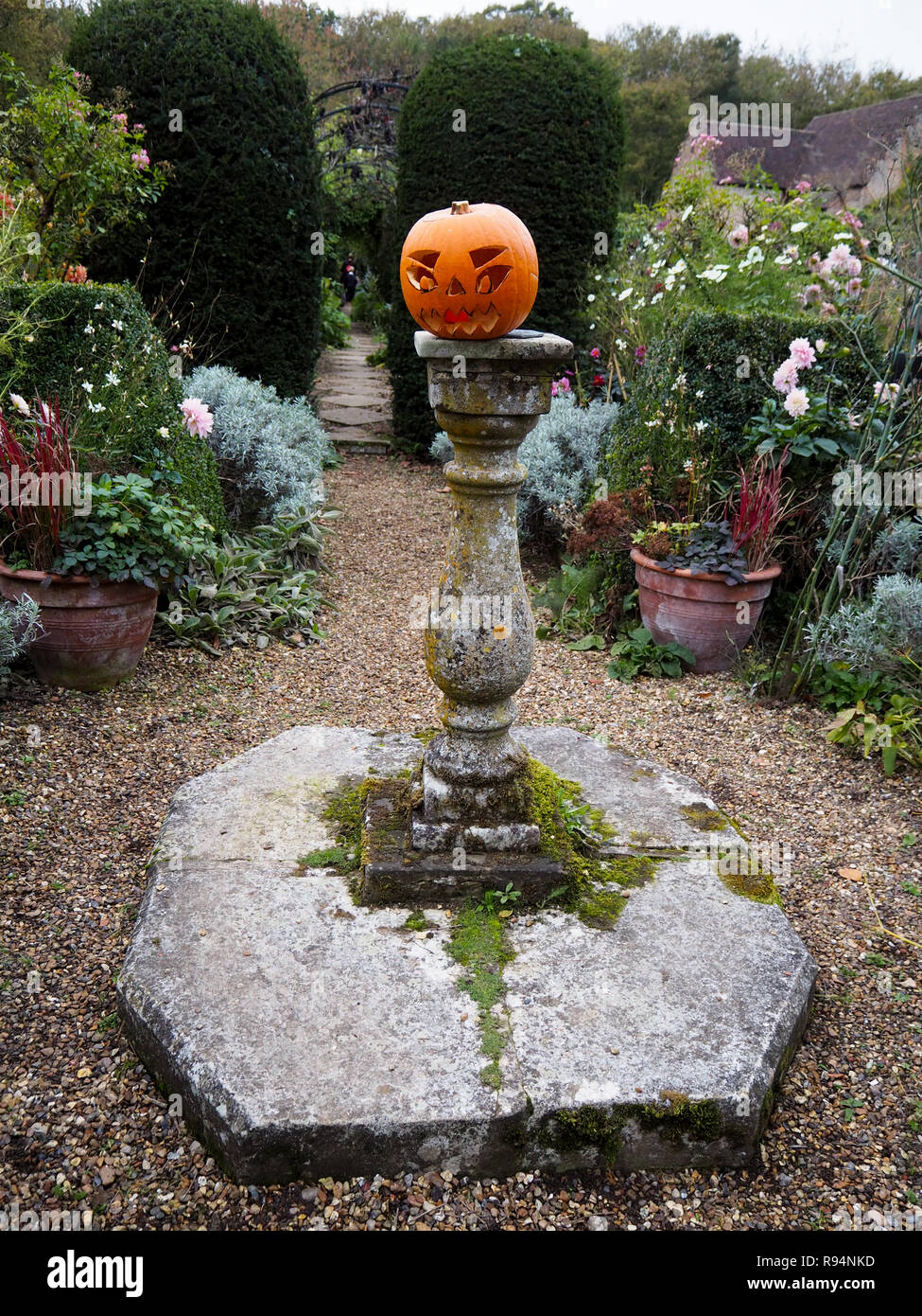 Halloween in Chenies Manor. Geschnitzten Kürbis auf der Sonnenuhr im Garten Weg durch den Torbogen gehen Ende Oktober. Hochformat. Stockfoto