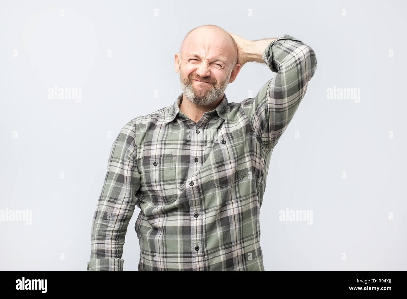 Elend und düsteren Kerl, runzelte die Stirn und Suchen unzufrieden, während Kratzen Kopf Stockfoto