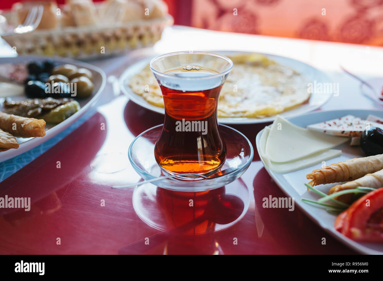 Close-up: Eine heiße Tasse duftenden schwarzen Tee. Zwei Platten mit vegetarischem Essen - frisches Gemüse und Käse, Kuchen und Getränke in Glas Rot, Tabelle Stockfoto