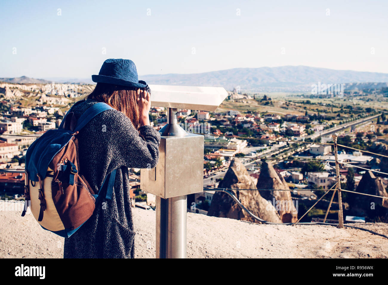 Ein Reisender mit einem Rucksack auf Sicht sieht durch ein Fernglas bei einem schönen Blick auf die Stadt von Göreme in Kappadokien in der Türkei. Reise. Stockfoto