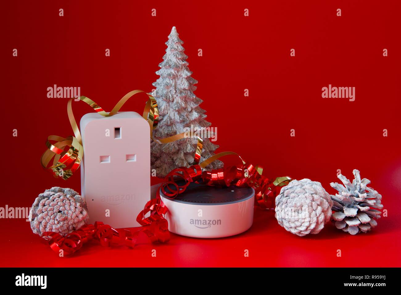 Amazon Echo Dot und Smart Plug mit Weihnachtsschmuck auf rotem Hintergrund Stockfoto